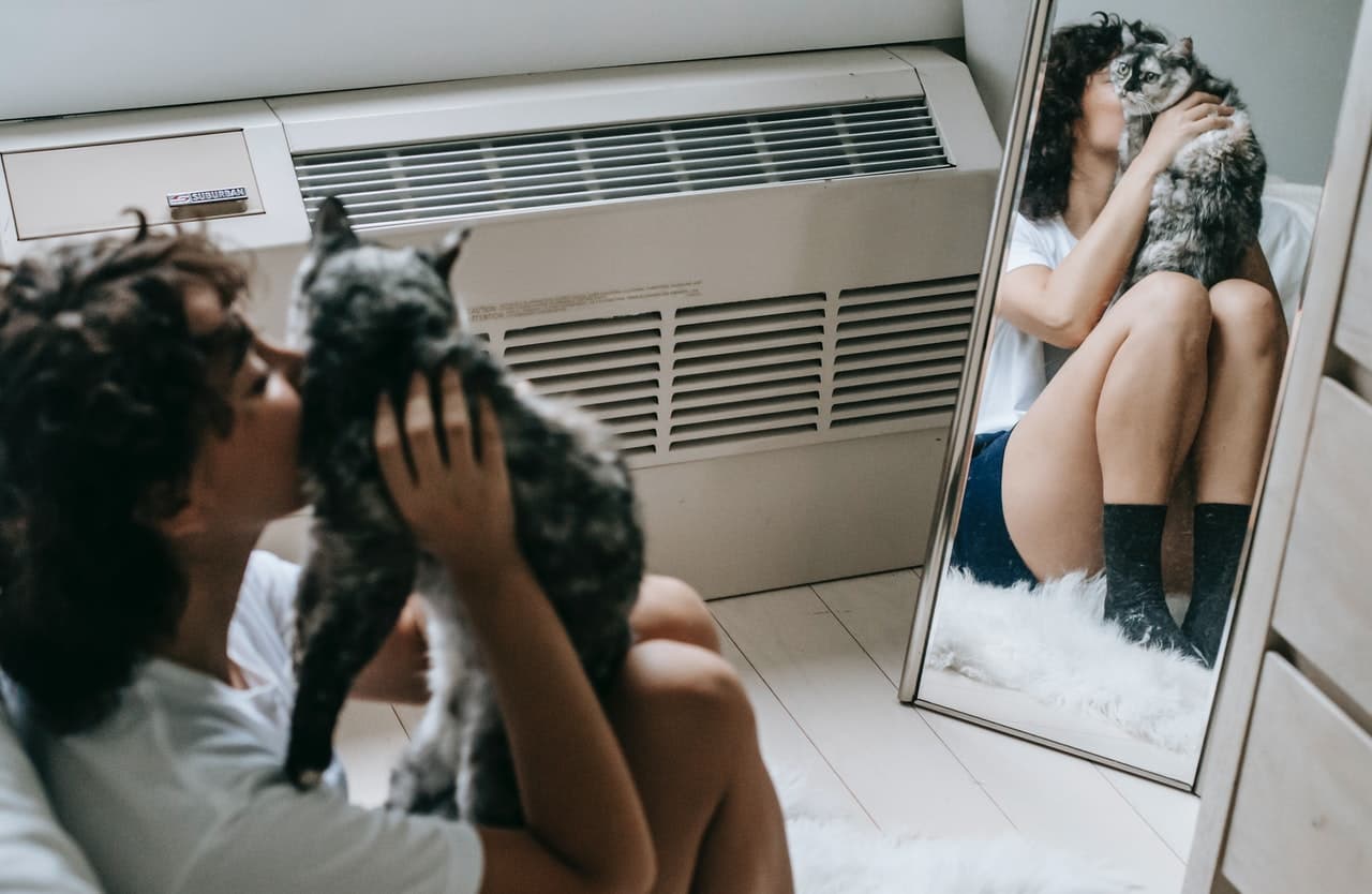 Woman kissing cat in mirror reflection